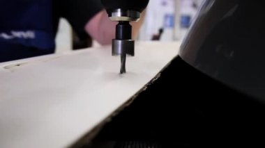 Adam beyaz ahşap yüzey delik açmak için elektronik vida sürücü kullanır.