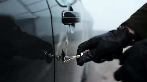 Руки в черной кожаной перчатке, держащий открывашку делает огромную дыру в двери автомобиля . — стоковое видео