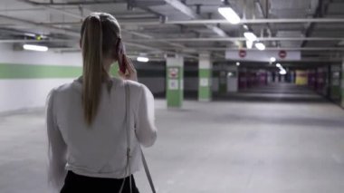Genç kadın, at kuyruğu, beyaz gömlek ve siyah etek garajda yürüyüş
