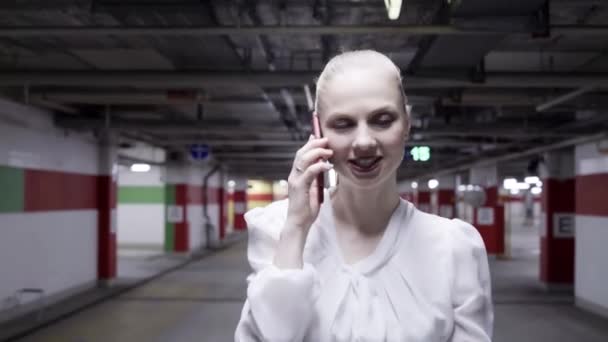 Caminhando jovem fêmea em camisa branca e saia preta no estacionamento subterrâneo — Vídeo de Stock