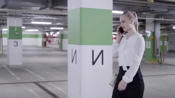 Söt kaukasiska kvinna i vit skjorta och svart kjol i undeground parkeringsplats — Stockvideo