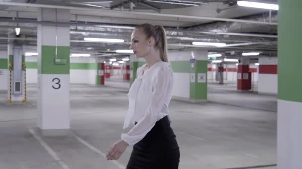 Ходячая красивая женщина в белой рубашке и черной юбке на неземной автостоянке — стоковое видео
