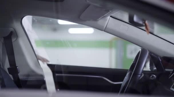 Ung kvinna i vit skjorta går ut ur undeground garage och får in bil — Stockvideo