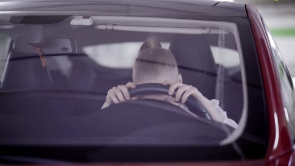 Απελπισμένος κυρία με αλογοουρά κάθεται σε κόκκινο αυτοκίνητο και βάζει το κεφάλι του στο τιμόνι — Αρχείο Βίντεο