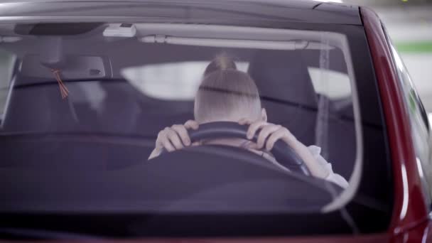 Desperate lady with ponytail sits in red car and puts head on steering wheel — Stock Video