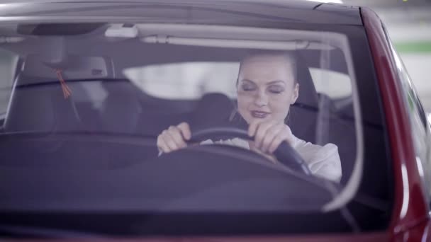 Leuke vrouw met een paardenstaart in rode auto achter stuur zit wanneer het begint te roken — Stockvideo