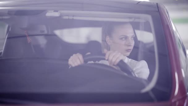 Mulher agradável na camisa branca senta-se no carro vermelho atrás do volante quando começa a fumar — Vídeo de Stock