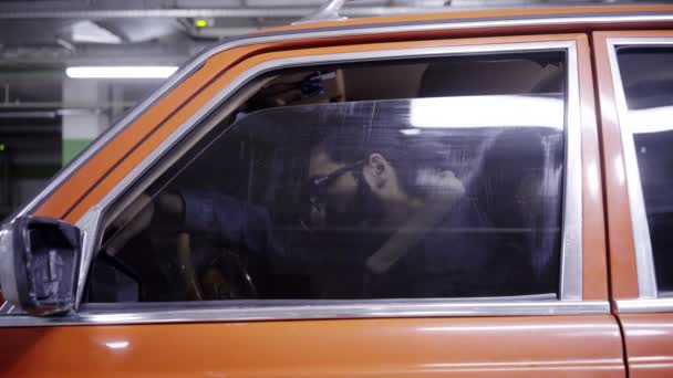 Carino maschio barbuto con lunghi capelli scuri apre il finestrino dell'auto rossa e inizia a parlare . — Video Stock