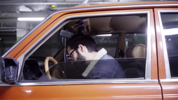 Homme barbu mature aux cheveux foncés ferme la fenêtre rouge de la voiture dans le garage souterrain — Video