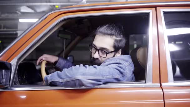 Beau mec barbu avec les cheveux longs regarde par la fenêtre de la voiture et conduit loin — Video