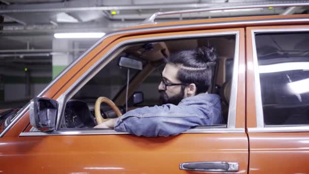 Gutaussehender bärtiger Mann mit langen Haaren schaut aus dem Autofenster und fährt davon — Stockvideo