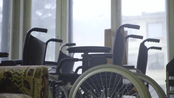 Demonstration of bunch of wheelchairs with white wheels put next to windows. — Stock Video