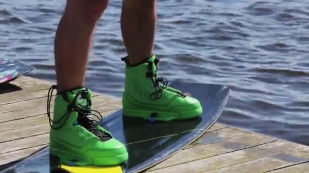 Muž na molu v zelených botách stojí na vodní wakeboarding připravený k zahájení vodního lyžování — Stock video