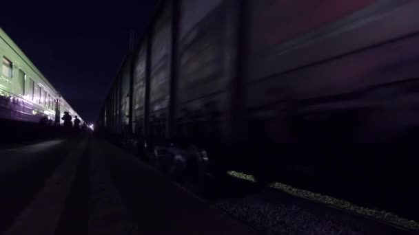 Платформа железнодорожного вокзала с людьми на ней и цепь движущихся вагонов — стоковое видео