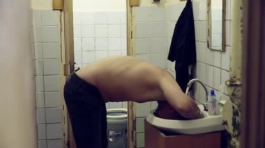 Çıplak gövde ile Olgun beyaz adam musluk suyu ile lavabo üzerinde başını yıkıyor