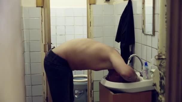 Mature white man with naked torso is washing his head above sink with tap water — Stock Video