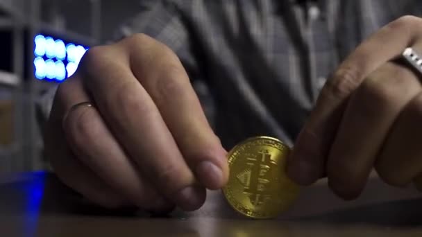 Mans hands are joyfully spinning big new gold bitcoin coin on brown table. — Stock Video