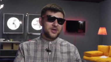 Işıklı genç adam maytapları yakar ve mobilyalı odada ellerinin arasına alır.