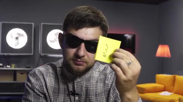 Молодий блогер ставить жовтий папір в гаманець перед камерою з посмішкою — стокове відео