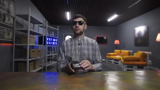 Homme vlogger avec des lunettes de soleil met grand Bitcoin d'or dans l'ancien portefeuille noir — Video
