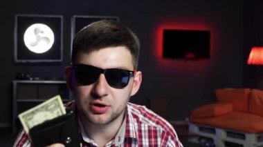 Güneş gözlüğü ile Yakışıklı adam kamera konuşuyor ve para ile cüzdan atar