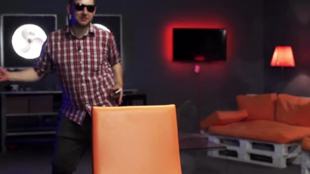 선글라스를 쓴 재미있는 수염이 있는 남자가 흡연실에서 적극적으로 춤을 추고 있습니다.. — 비디오