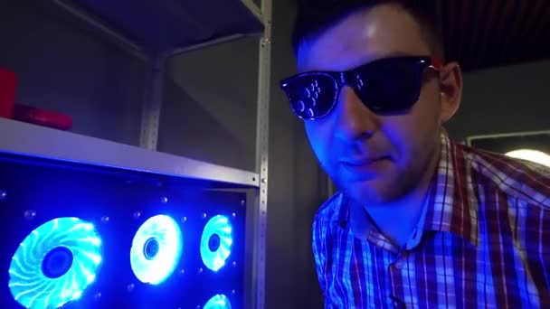 Divertido barbudo con gafas de sol está de pie junto a refrigeradores iluminados azules — Vídeo de stock