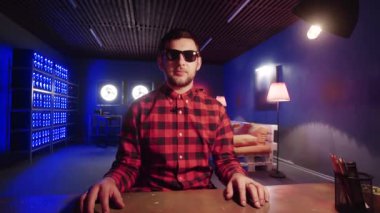 Genç adam masanın arkasında oturuyor, aydınlatmalı soğutuculu odada el hareketlerini kullanıyor.