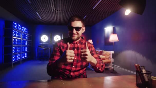Aantrekkelijke man zit aan het Bureau, toont duimen omhoog in de kamer met verlichte koelers — Stockvideo