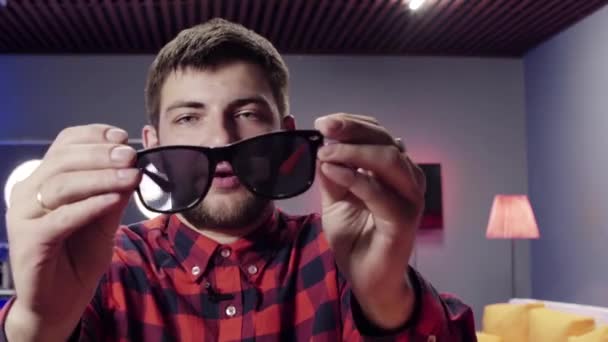 Schöner Kerl nimmt Sonnenbrille ab und massiert seine Ohren in schön eingerichtetem Zimmer — Stockvideo