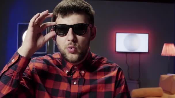 Ωραίος έξυπνος τύπος που βάζει γυαλιά ηλίου δυναμικά μιλά με την κάμερα — Αρχείο Βίντεο