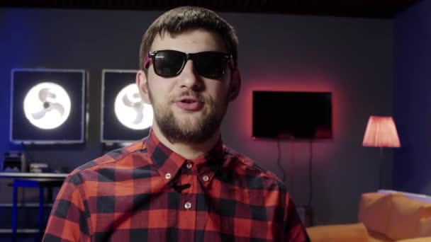 Cool active bearded guy wearing sunglasses emotionally speaks at camera — Stock Video