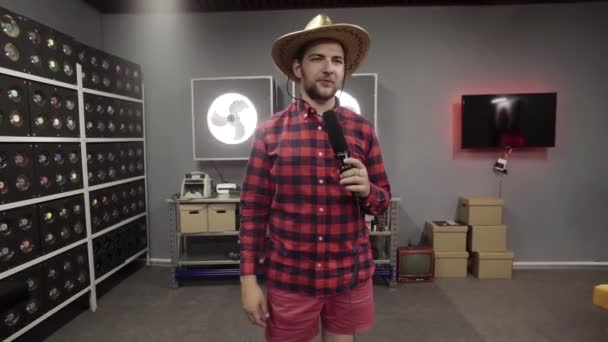 Jonge grijze man met baard draagt Mexicaanse hoed houdt microfoon vast en zingt. — Stockvideo