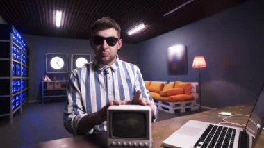 Adam masaya küçük eski gri Tv koyar sonra arkasından atar .