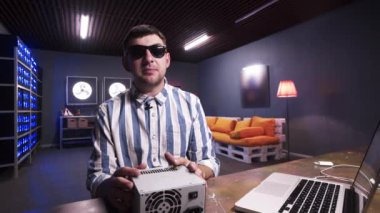 Karizmatik sakallı adam soğutucu ile güç kaynağı kutusunu tutan kamera konuşuyor