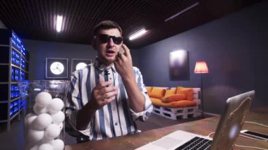 Karizmatik sakallı adam elinde masa tenisi topları tutarak kamera konuşuyor