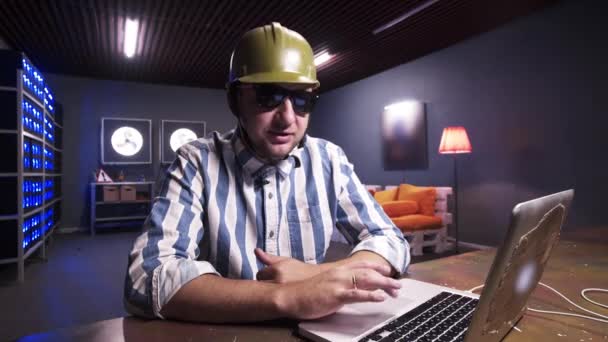 Attractive bearded guy put on sunglasses and green safety construction helmet. — Stock Video