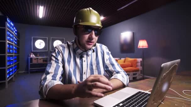 Young bearded male put on sunglasses and green safety construction helmet. — Stock Video