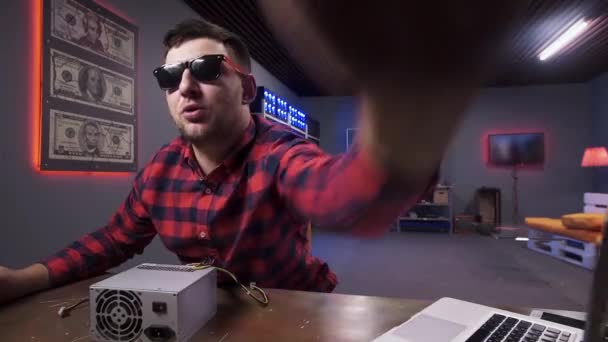 Fiatal szakállas férfi ad öt kamerát, dobozos tápegységgel az asztalon. — Stock videók