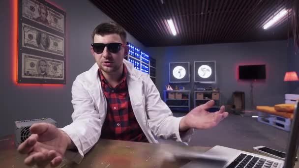 Beyaz laboratuvar önlüğü ile güneş gözlüğü ile Adam kameraya bakar ve zarfyakalar — Stok video