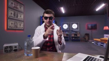 Beyaz laboratuvar önlüğü giyen çekici adam plastik şişe ile masanın arkasında oturur