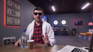 Beyaz laboratuvar önlüğü giyen karizmatik adam plastik şişe ile masanın arkasında oturur