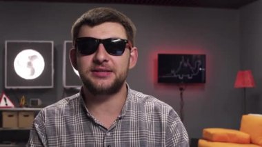 Sakallı komik esmer adam modern döşenmiş odada kamera bakarak görüşmeler.