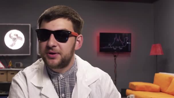 Sobres vacíos caen sobre un joven guapo con gafas de sol y bata de laboratorio blanca — Vídeos de Stock