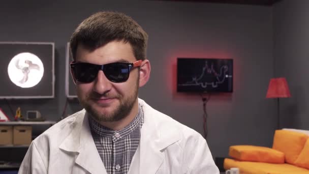 Sobres vacíos caen sobre lindo hombre joven con gafas de sol y bata de laboratorio blanca — Vídeos de Stock