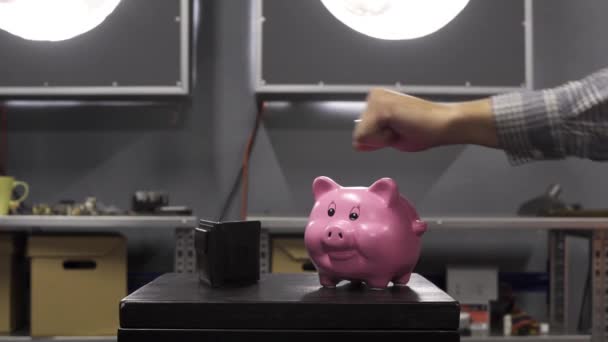 男性手显示大拇指对小猪银行放在桌子上与钱包. — 图库视频影像