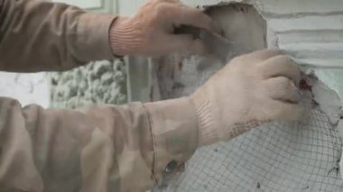 Erkek işçilerin elleri yeşil duvara metalik tel ağı doğru bir şekilde bağlar.