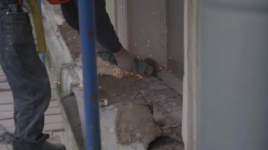 İnşaat işçisi duvarın eski toz metalik kısmını kesmek için kesme makinesi kullanır