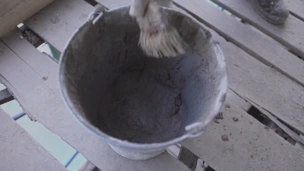 Worker hands accurately take out wet concrete mass with paint brush from bucket — 비디오