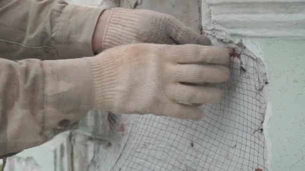 Le mani dei lavoratori edili fissano accuratamente la rete metallica sulla parete verde . — Video Stock